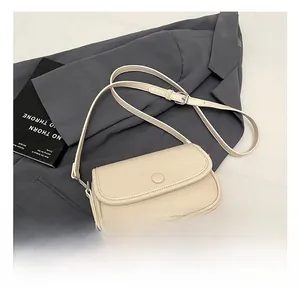 Close-up of cream-colored litchi grain leather flap bag with adjustable shoulder strap