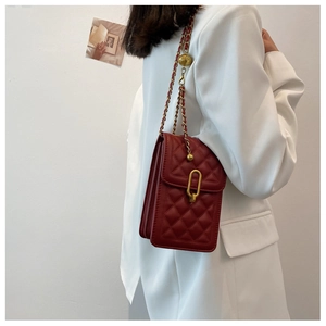 Detail of red quilted square bag with gold chain strap and adjustable ball accessory