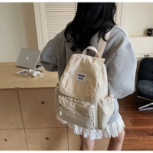 Vista posteriore di uno zaino in tela beige che mostra vestibilità su modella