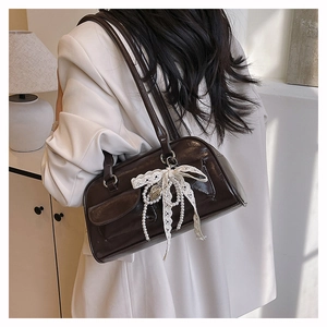 Détail du sac porté épaule marron avec nœud en dentelle et breloques de perles en cœur