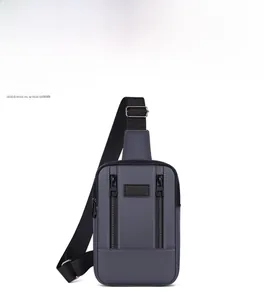 Detail of gray washed denim crossbody bag featuring dual vertical zippers and adjustable strap