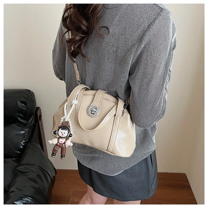 Sac bowling beige avec fermoir en métal et charm de dessin animé porté par mannequin