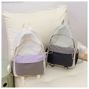 Close-up of nylon outdoor backpacks with drawstring side pockets on a cozy white sofa