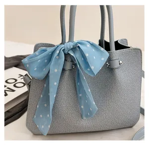 Détail du sac seau bleu clair tissé avec foulard à pois et finitions métalliques élégantes