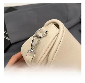 Detailed close-up of premium silver metal hook and pebble grain leather on cream handbag