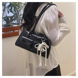 Détail du sac noir brillant avec deux poches avant et pendentif en perles et dentelle
