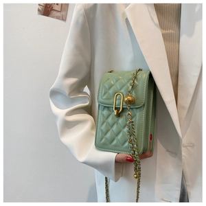 Detail of light green quilted crossbody bag with gold chain and metal hardware