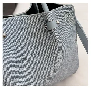 Gros plan d'un sac à main bleu clair en tissu texturé avec boules en métal et fine bandoulière