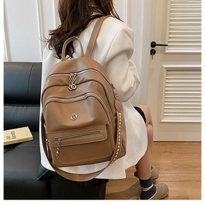 Brown lychee leather backpack showing multi-pocket design and woven shoulder strap