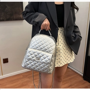 Schicker silberner Stepprucksack mit Metallkettenriemen auf dem Rücken eines Models