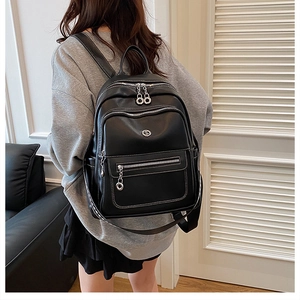 Detail of black leather backpack with silver metal zippers and multi-compartment design