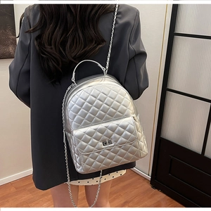 Detailansicht des silbernen gesteppten Lederrucksacks mit Metallic-Textur und Kettenriemen