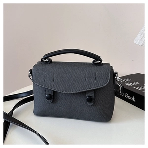 Detail of grey textured woven fabric mini square bag with black leather handle and strap