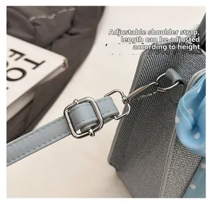 Détail de la bandoulière réglable en PU avec boucle argentée sur un sac seau en tissu