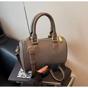 Detailed macro view of woven mocha brown boston bag with golden hardware and leather strap