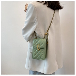 Detail shot of light green quilted crossbody phone bag with gold chain strap on a model