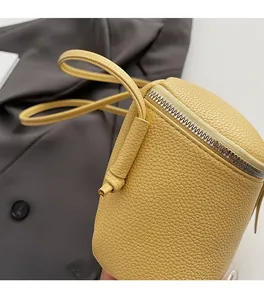 Detail der gelben Zylindertasche aus strukturiertem Leder mit silbernem Reißverschluss