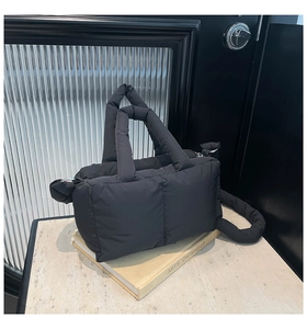 Détail du sac cabas matelassé noir avec poignées épaisses sur une surface en marbre