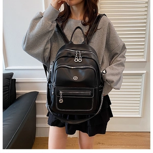 Detail shot of black leather backpack with silver hardware zippers and metallic oval logo