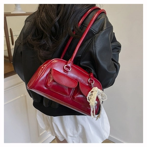 Détail d'un grand sac bandoulière en cuir verni rouge avec chaîne décorative en perles