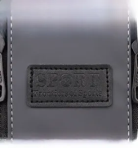 Macro view of the leather SPORT logo patch with white stitching on washed denim crossbody bag