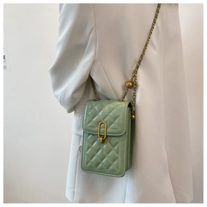 Detail of mint green quilted chain bag with gold adjustable bead on white blazer