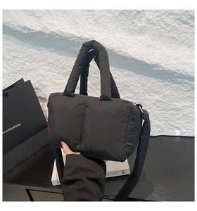 Détail du sac fourre-tout matelassé noir avec poignées rembourrées et bandoulière