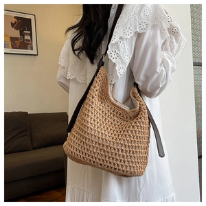 Détail du sac seau en paille tissée avec bretelles en cuir marron pour plage d'été