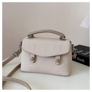 Detail of woven texture and light brown leather trim on a vintage square handbag