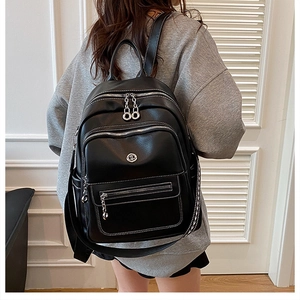 Close-up of black leather backpack detailing silver zippers and metallic logo accents