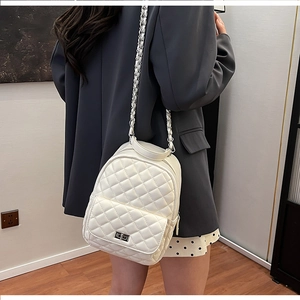 Detail eines weißen Stepprucksacks mit Kettenriemen an der Schulter einer Person