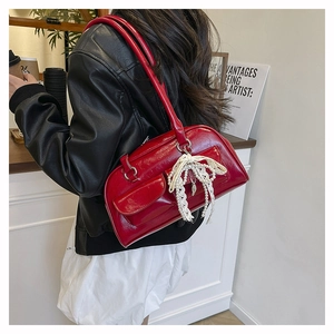 Détail du sac bowling rouge avec nœud en dentelle et perles porté par un mannequin