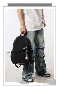 Dettaglio della borsa a tracolla nera impermeabile con logo STLANGS e ciondolo baseball