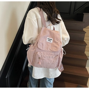 Vista posteriore dello zaino in nylon rosa con etichetta minimalista su una scala moderna