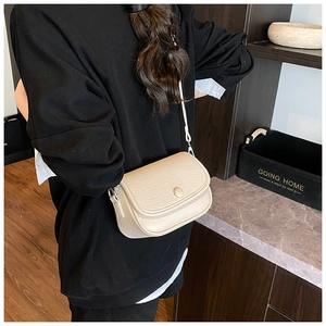 Rear view of model wearing a creamy white saddle bag with pebble leather texture
