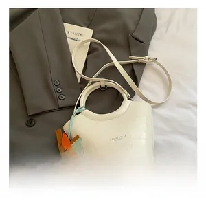 Detail of white crocodile pattern bucket bag with horse charm and logo on grey blazer