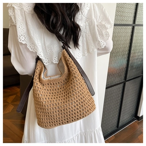 Détail du sac seau en paille tressée avec texture crochetée et bandoulière en cuir brun