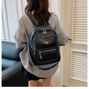 Detail of black PU leather backpack with silver zippers and striped shoulder straps