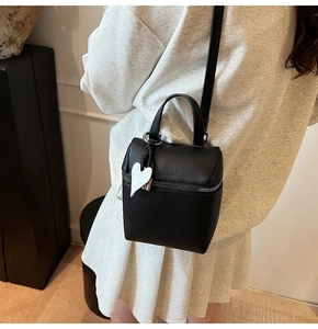 Dettaglio mini borsa a secchiello in pelle martellata nera con ciondolo a cuore bianco e zip