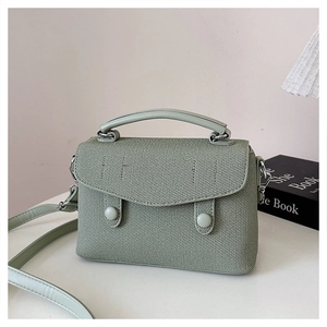 Detail of light green textured crossbody bag with flap and dual round button fasteners
