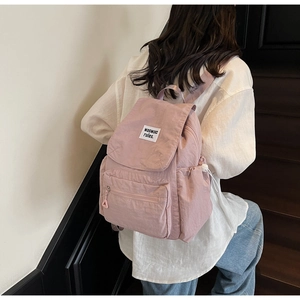 Dettaglio dello zaino in nylon rosa chiaro con tasca laterale a coulisse ed etichetta bianca
