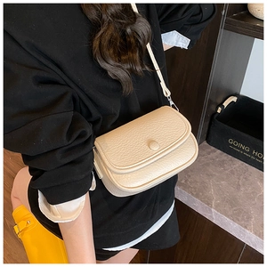 Close-up of off-white litchi grain leather crossbody bag with minimalist round snap closure