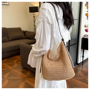 Gros plan d'un sac en paille tressée avec bandoulière en cuir réglable porté par un modèle