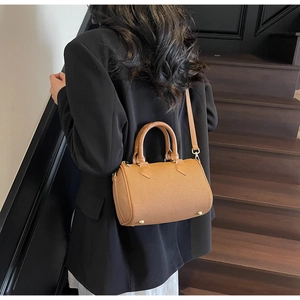 Detail of tan canvas Boston bag with leather handles and gold studs on a wooden staircase