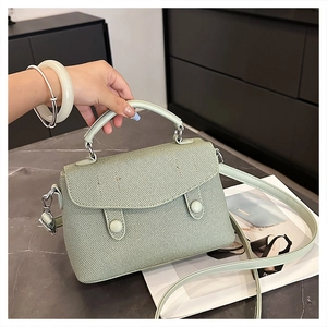 Detail view of mint green crossbody bag with textured woven surface and stylish handle
