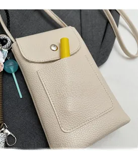 Vue détaillée du sac téléphone en cuir beige grainé avec fermoir magnétique et poche