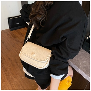 Detail of beige lychee textured leather crossbody bag with silver hardware and strap
