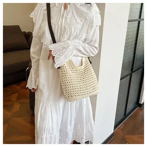 Détail d'un sac cabas tissé beige avec motif crocheté ajouré et bandoulière marron