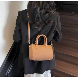 Close-up of brown barrel bag featuring gold zippers and adjustable shoulder straps