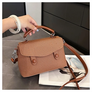 Detail of brown woven texture and silver hardware on a vintage crossbody flap bag